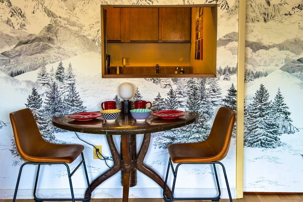 [1st Floor] Dining table for 2 with the a wallpaper backdrop of the Alps! Makes you feel like you are eating in the outdoors. Kitchen has a complete set of plates, bowls, mugs, and utensils, including a plastic set of plates and utensils for kids.